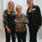 Ann Jutzi stands between Sara Villanueva, Benevilla Vice President of Donor Relations, and Joanne Byers, Benevilla President and CEO, while holding the Bill Wolfrey Community Service Award at the Gratitude Celebration Luncheon on November 18.