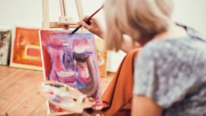 Caregiver painting at an easel during a Benevilla art activity focused on relaxation and creative expression.